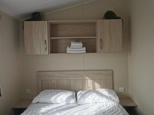 a bedroom with a bed with white sheets and wooden cabinets at 3 Bedroom Mersea Beach Retreat-Getaway by the Sea in West Mersea
