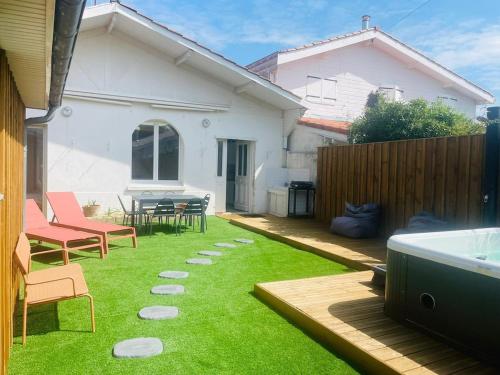 a backyard with grass and chairs and a hot tub at Cabane de Pénélope avec spa privé centre-ville et plage in Andernos-les-Bains