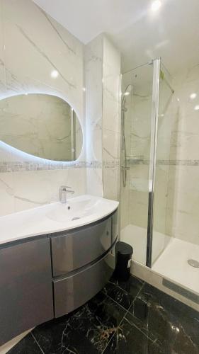 une salle de bain blanche avec un lavabo et une douche dans l'établissement Lux Home Le Marais, à Paris
