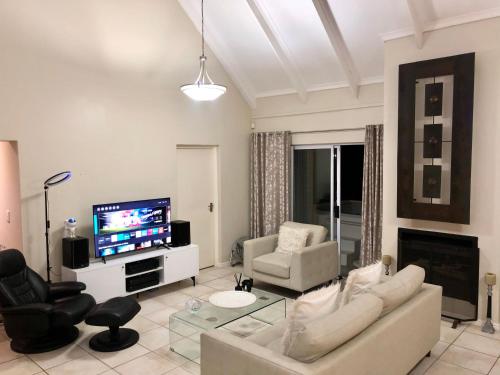 a living room with a couch and chairs and a television at #SilverSands Coastal Retreat in Betty's Bay in Bettyʼs Bay