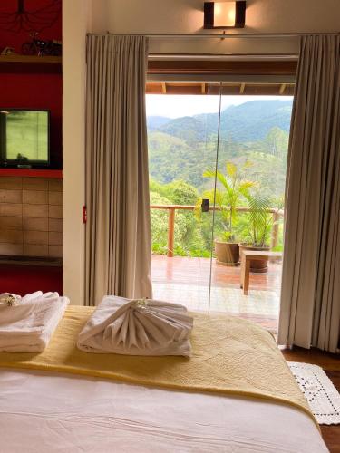 a bedroom with a bed with a view of a balcony at Chalé nas montanhas em São Francisco Xavier in São Francisco Xavier