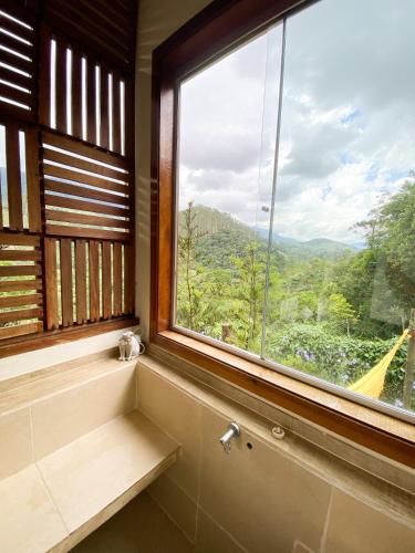 a bathroom with a large window with a view at Chalé nas montanhas em São Francisco Xavier in São Francisco Xavier