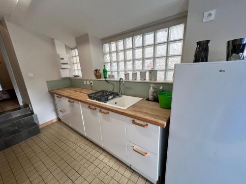 une cuisine avec un évier et un réfrigérateur blanc dans l'établissement La Pension, à Vierzon
