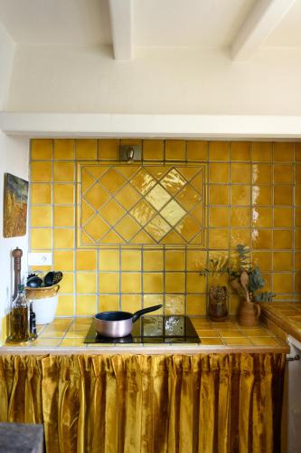 Una encimera de azulejos amarillos con una sartén encima. en Haven of peace in luberon, en Cabrières-dʼAvignon