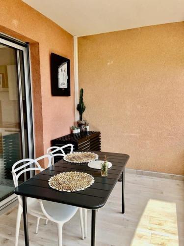 a black table and chairs in a room at Casamea - Marinella T2, Vue Mer, Plage à 2min, in Ajaccio