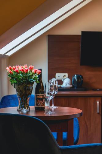 a table with two wine glasses and a vase with flowers at Nad Borkiem in Kosarzyn