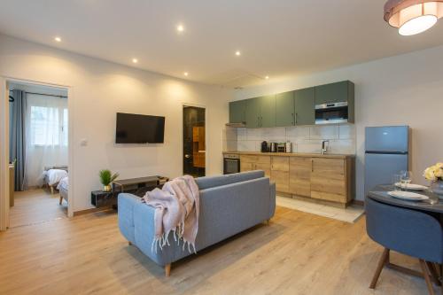un soggiorno con un divano blu e una cucina di La chute des feuilles - 2 Lits simples - T2 Hyper centre a Abbeville
