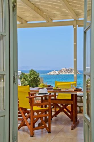 a patio with a wooden table and yellow chairs at Ydreos Studios & Apartments in Mikri Vigla