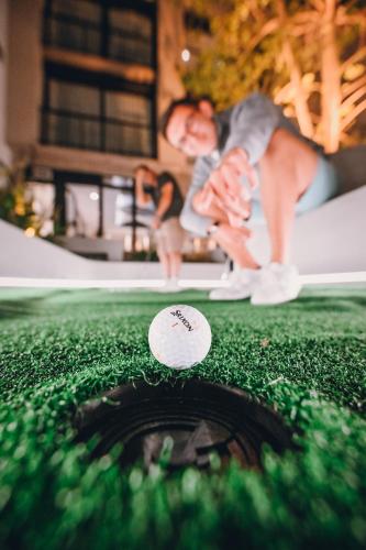 a man sitting next to a golf ball on a putting green at Hotel Denver Mar del Plata in Mar del Plata