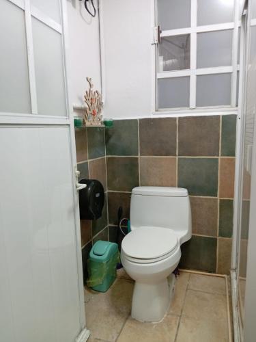 a bathroom with a toilet and a tiled wall at Depto con PISCINA PUENTE DEL MAR ACAPULCO in Acapulco