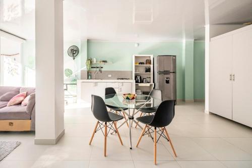 Una cocina y un comedor con una mesa de cristal y sillas. en Casa Oasis, en Villavicencio