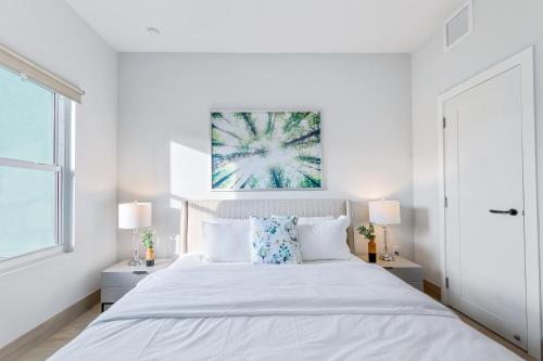 a white bedroom with a large bed and two lamps at Affordable Luxury Apartments, 3 Min to Beach in West Bay