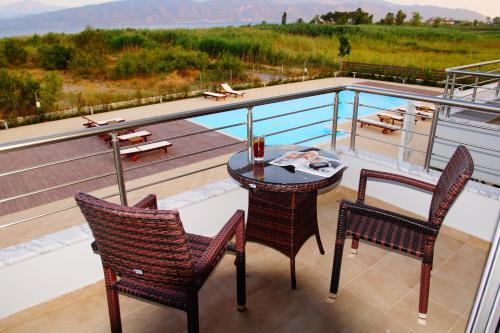 a balcony with a table and chairs and a pool at Cavos Fokidos in Chiliadou
