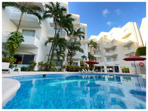 a swimming pool in front of a building with palm trees at Adhara Express in Cancún