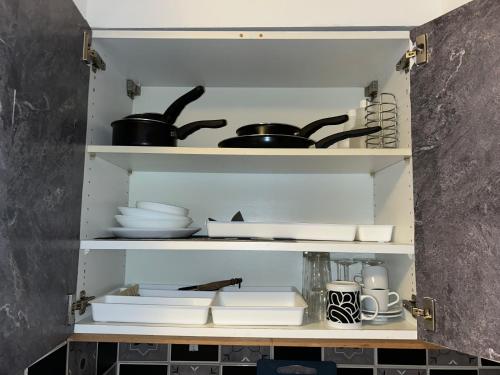 - une étagère avec de la vaisselle, des casseroles et des poêles dans la cuisine dans l'établissement Studio in city center, à Strasbourg