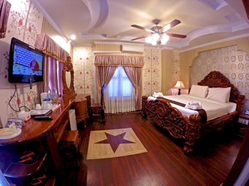 Dormitorio con cama, escritorio y TV en King Fy Hotel, en Battambang