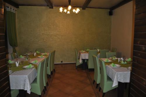 a dining room with tables and green chairs at Vila Veche in Haţeg