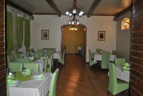 a dining room with tables and green chairs at Vila Veche in Haţeg