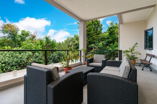 a balcony with wicker furniture and a view of trees at Aran Apartments in Au Cap