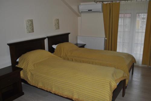 a bedroom with two beds with yellow blankets at Vila Veche in Haţeg