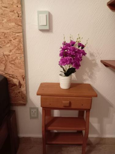 a table with a vase of purple flowers on it at Depto con PISCINA PUENTE DEL MAR ACAPULCO in Acapulco