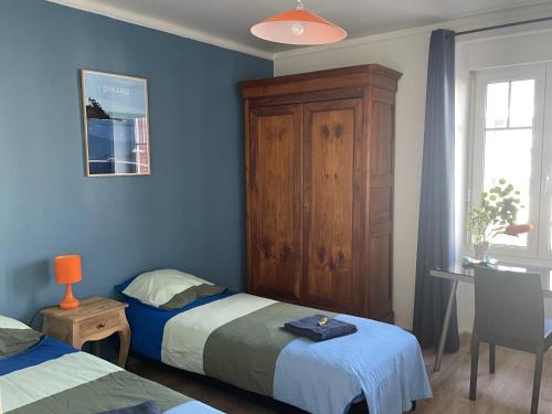 Un dormitorio con dos camas y un armario de madera. en Appart de Manuela, en Saint-Malo