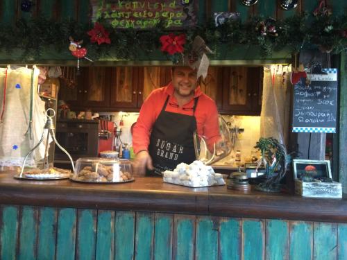 a man in an apron preparing food at a counter at Feggaropetra Inn Magic Mountain House in Palaios Panteleimon