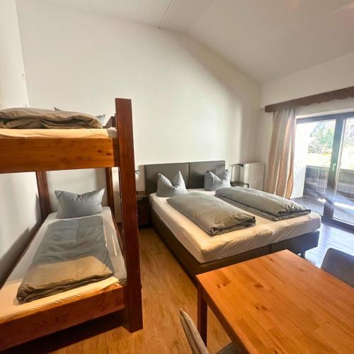 a room with two bunk beds and a table at Pension Almhof Baumgarten in Bad Reichenhall