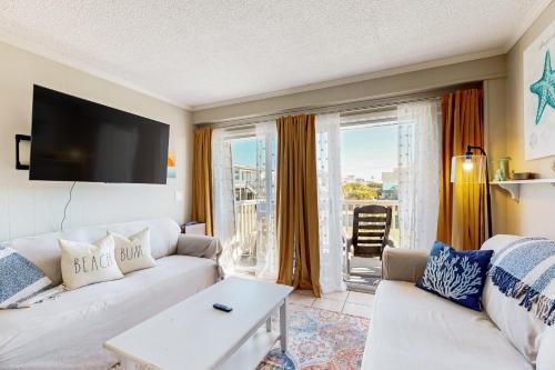 a living room with a white couch and a tv at HB289 Feel the Burn in Holden Beach