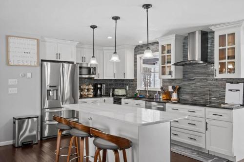 a kitchen with white cabinets and a large island with bar stools at Serene Lakeside Retreat with Hot Tub Near Gunstock in Gilford