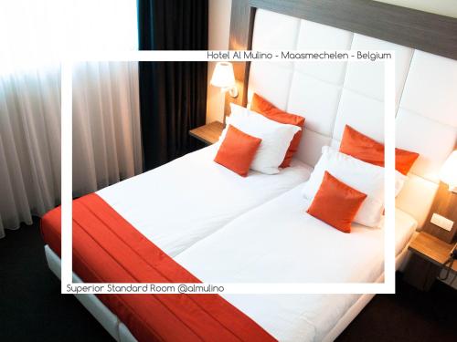 a hotel room with a bed with orange and white pillows at Hotel AL Mulino in Maasmechelen