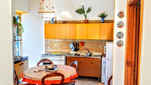 a kitchen with a table and a kitchen with yellow cabinets at Casa Filomena in Ischia
