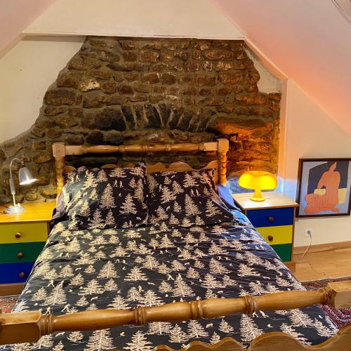 un lit dans une chambre avec un mur en pierre dans l'établissement Une maison à la campagne, à Saint-Mars-sur-la-Futaie