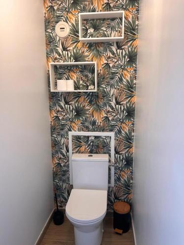 La salle de bains est pourvue de toilettes et de papier peint tropical. dans l'établissement Appartement spacieux de standing CALAIS PLAGE, à Calais