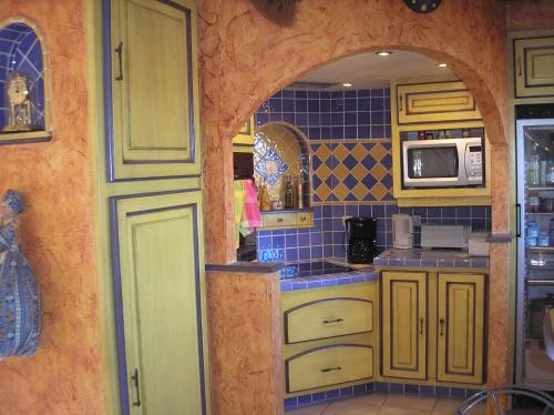 - une cuisine avec des murs carrelés jaunes et bleus dans l'établissement Au Bonheur et Liberté, à Meyrargues