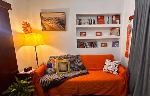 an orange couch with pillows in a living room at Apartamentos Gharb Diem in Tavira