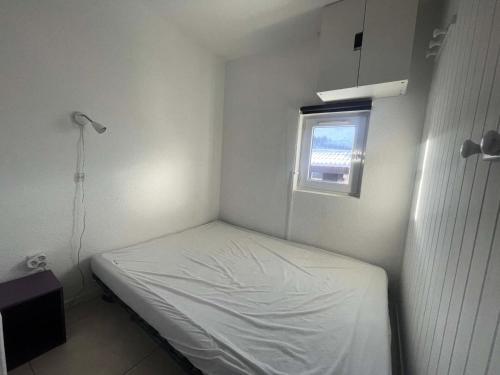 Cette petite chambre blanche dispose d'un lit et d'une fenêtre. dans l'établissement Résidence Arc En Ciel B - T2 cosy à proximité du départ des pistes, vue sur la montagne MAE-0551, à Vénosc