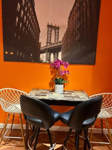 a table with chairs and a vase with flowers on it at Cozy Apartments Woodside near Manhattan in Queens