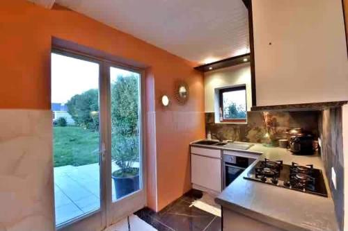 Il comprend une cuisine aux murs orange et une grande fenêtre. dans l'établissement Le cottage bohème, à Rimoux