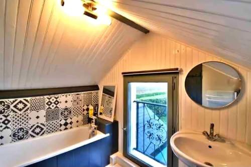 une salle de bain avec une baignoire, un lavabo et une fenêtre dans l'établissement Le cottage bohème, à Rimoux