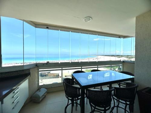 a table and chairs in a room with a view of the ocean at Apartamento Luxo Vista Mar Andrei Noriller in Arraial do Cabo