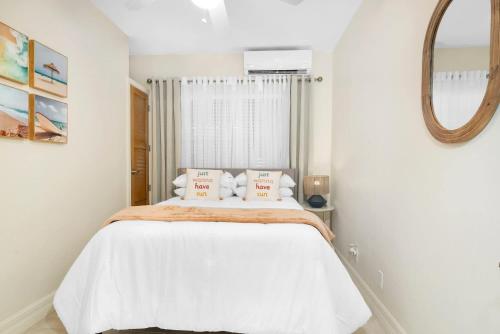 a bedroom with a bed with white sheets and a mirror at Relaxing Island Retreat Steps to Grace Bay Beach in Long Bay Hills