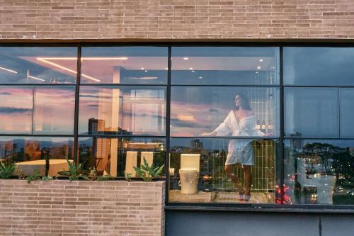a woman standing in a window of a building at Hotel Sexto by Icono in Armenia