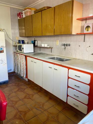 a kitchen with white cabinets and a sink at Casa en Mar del Plata - Colinas de Peralta Ramos in Mar del Plata
