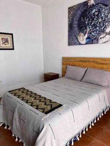 a bed in a bedroom with a painting on the wall at Casa Aida in San Pablo Villa de Mitla