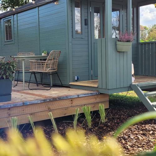 a blue house with a table and a chair on a deck at Boholodges 2 pers met privé hottub in Meerssen