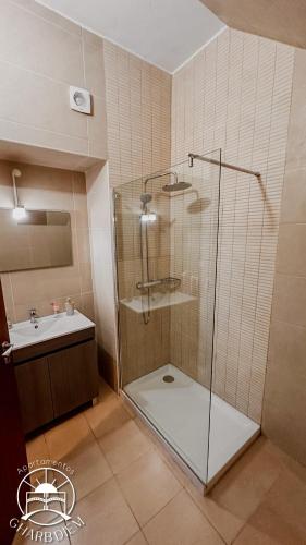 a bathroom with a glass shower and a sink at Apartamentos Gharb Diem in Tavira