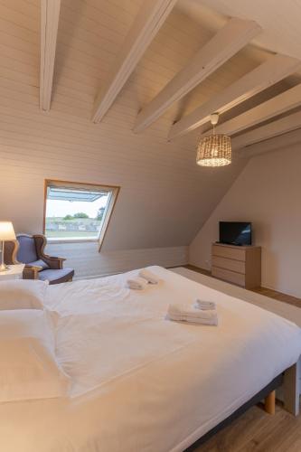 une chambre avec un grand lit blanc et une fenêtre dans l'établissement TY CARN - Belle maison bretonne à 100m de la mer, à Ploudalmézeau