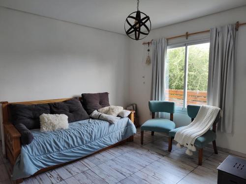 a living room with a bed and two chairs and a window at Sierra Bonita - Viví en Armonía in Sierra de los Padres