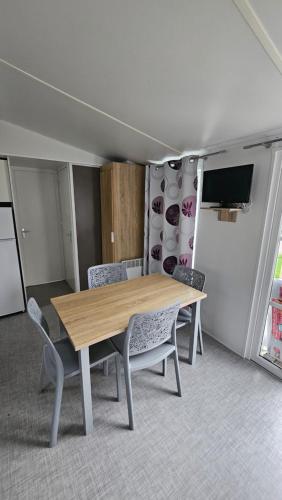 a dining room with a wooden table and chairs at Mobile Home XL Camping 5 étoiles in Houlgate